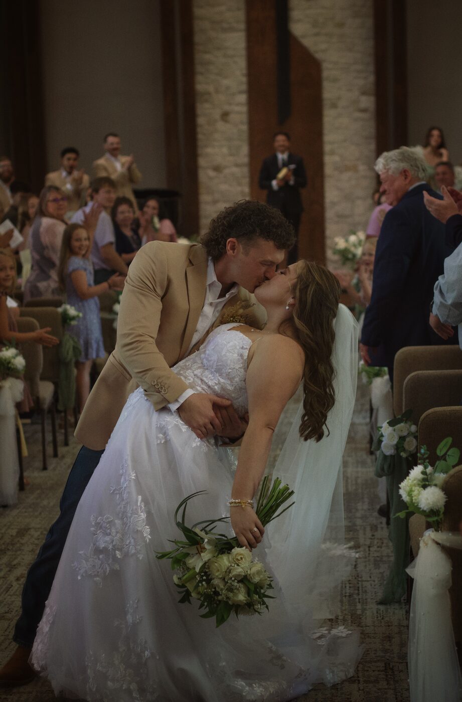 Bride and groom kissing mid-dip in the aisle